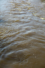 Brown River Water Flowing in Natural Outdoor Setting with Gentle Ripples and Reflections