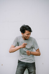 Anxious young man gesturing nervously against a stark white wall