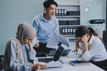Young asian businesswoman suffering from headache while colleagues arguing and blaming her for bad...