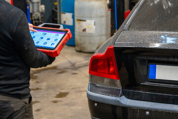Car diagnostic specialist using electronic tablet scanner in automotive repair garage. Mechanic...