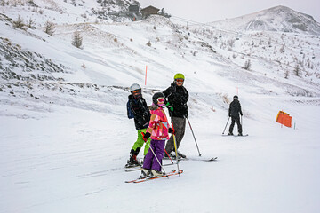 family skiing at italian alpine ski resort in bad weather. school holidays and safety