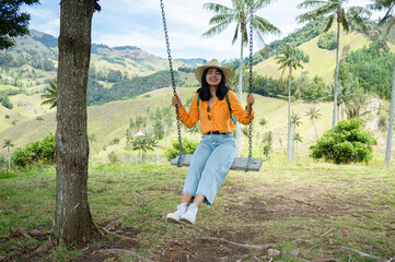 Tourist swinging on a swing in La Samaria Valley a wax palm Forest in Colombia