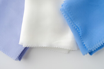 Stack of pastel-colored plain hijabs in light blue, white, and lavender on a clean white background. Elegant and minimalist look, perfect for Muslim fashion catalog