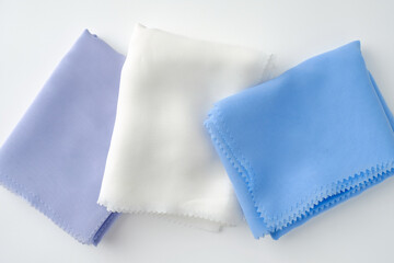 Stack of pastel-colored plain hijabs in light blue, white, and lavender on a clean white background. Elegant and minimalist look, perfect for Muslim fashion catalog
