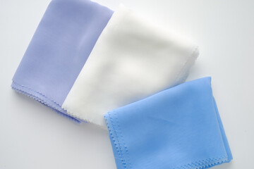 Stack of pastel-colored plain hijabs in light blue, white, and lavender on a clean white background. Elegant and minimalist look, perfect for Muslim fashion catalog