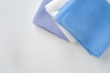 Stack of pastel-colored plain hijabs in light blue, white, and lavender on a clean white background. Elegant and minimalist look, perfect for Muslim fashion catalog