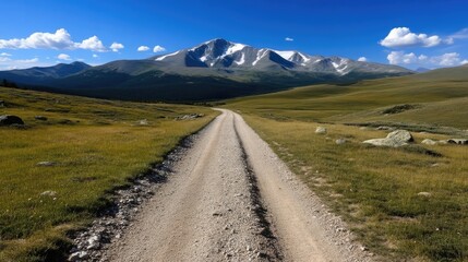 Fototapeta premium Mountainous dirt road leading to snowy peak