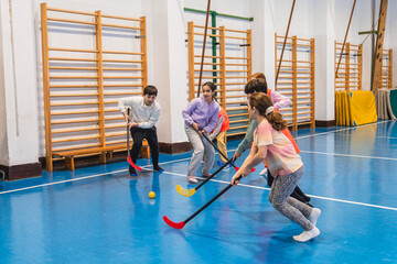 Elementary school students enjoying a dynamic game of floorball during gym class, promoting teamwork and physical activity