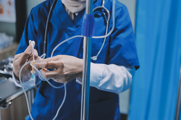 A nurse with IV drip and patient in bed in hospital room.
