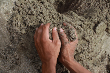 Hands holding a handful of sand, feeling the granular texture and nature's raw material