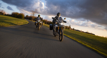 Drivers riding motorcycle on empty road during sunset, spring mountains