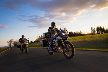 Drivers riding motorcycle on empty road during sunset, spring mountains