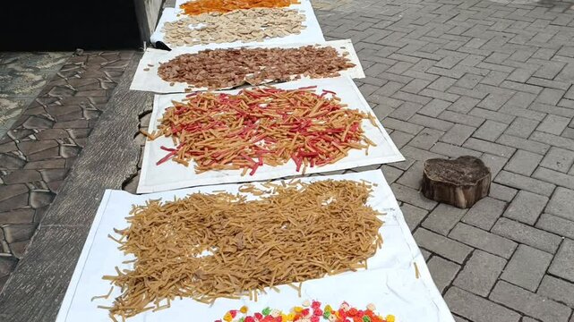 Raw unfried crackers are spread across white trays and left to dry naturally under sunlight before frying.