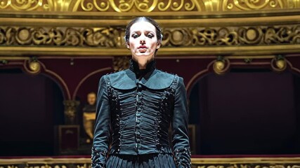Elegant performer in dramatic costume captivates the audience during a theatrical production at a historic theater venue