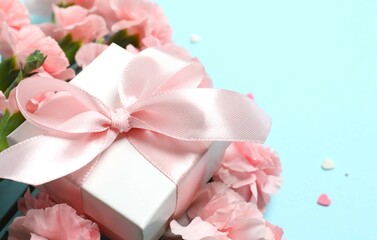 Beautiful bouquet of pink carnations with gift box on a colored background