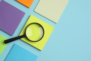 Magnifying glass with paper stickers on color background