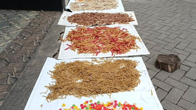 Raw unfried crackers are spread across white trays and left to dry naturally under sunlight before frying.
