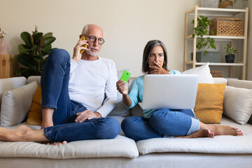 Mature married couple having financial problems calling bank. Female holding credit card with...