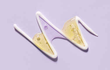 cosmetic smear of white creamy texture with drops of serum on pastel background close-up