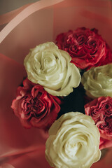 A lovely bouquet of roses and white roses with red stems is displayed in a vase with a pink ribbon