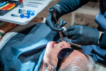 Dentist injecting anesthesia to senior woman patient in dental clinic