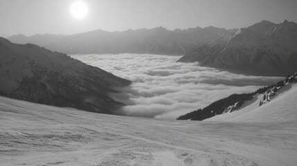 Serene monochrome vista of snow covered mountain range with cloud inversion under bright sunlight in winter landscape