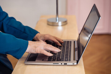 An elderly woman in a blue blazer engages with her laptop at a clean and modern workstation