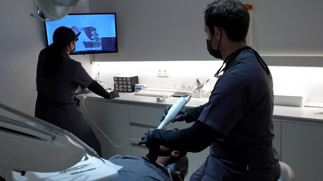 Dentist performing a digital scan of patient's teeth using a 3d intraoral scanner in a modern dental clinic