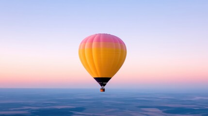 Obraz premium Colorful hot air balloon floats above a hazy landscape at dawn