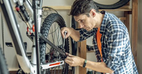 A male bicycle mechanic repairs a mountain bike in a workshop. The concept of preparation for the...