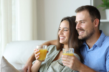 Happy couple at home relaxing drinking orange juice