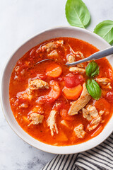 Tomato chicken soup with vegetables and basil.