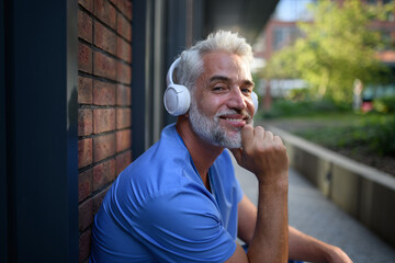 Healthcare worker relaxing with music outside hospital.