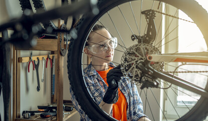 Obraz premium Woman is performing maintenance on mountain bike. Concept of fixing and preparing the bicycle for the new season