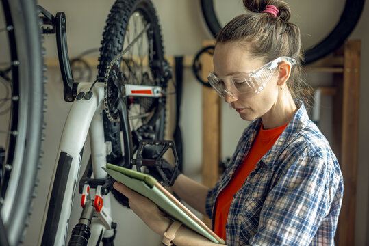 Woman is performing maintenance on mountain bike. Concept of fixing and preparing the bicycle for the new season