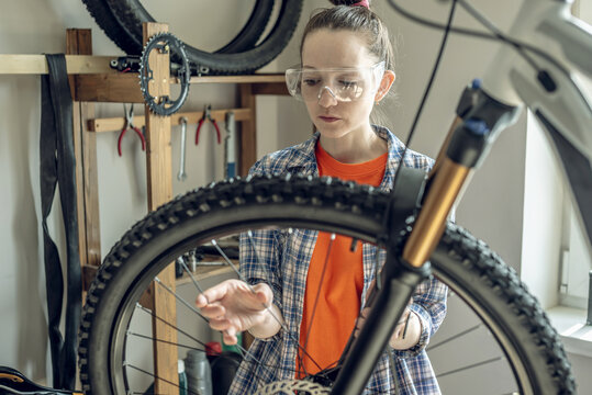 Woman is performing maintenance on mountain bike. Concept of fixing and preparing the bicycle for the new season