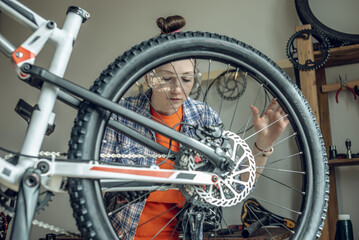Woman is performing maintenance on mountain bike. Concept of fixing and preparing the bicycle for the new season
