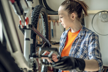 Woman fixing a mountain bike in a repair shop. Concept of preparation for the new season, repair and maintenance