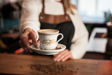 Blonde German barista smiling while serving a cup of coffee in a cozy café bar setting