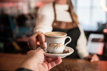 Friendly blonde barista serving coffee to go in a welcoming café bar in Germany