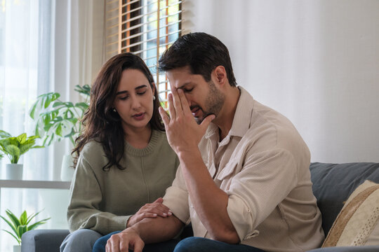Supportive couple in emotional moment at home as woman struggles with sadness and stress, expressing