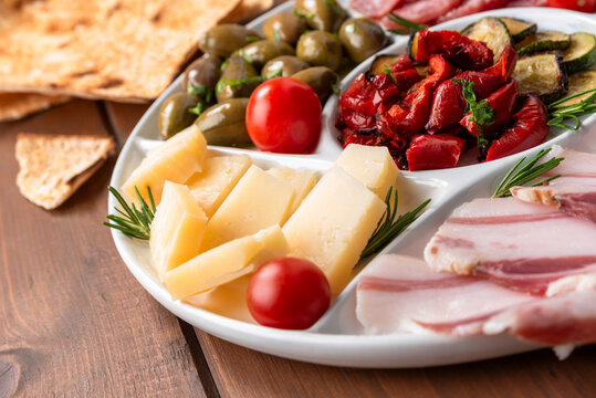 Vassoio con formaggio, pancetta, peperoni, zucchine e olive, stuzzichini italiani 
