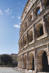 Naklejka premium The colosseum, an ancient amphitheater in rome, stands majestically under a clear blue sky, showcasing its architectural grandeur and historical significance