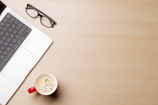 A clean and minimal desk setup featuring a laptop and a coffee cup