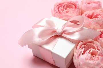 Beautiful pink peony roses and gift box on a color background