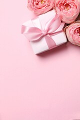 Beautiful pink peony roses and gift box on a color background