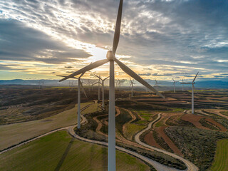 Wind turbines over agricultural landscape in Zaragoza, Spain, captured from above at sunset, illustrating renewable energy, climate adaptation and sustainable land use.