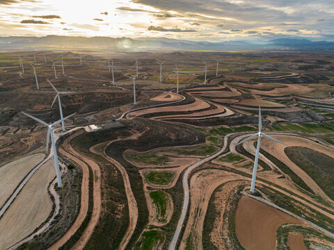 Multiple wind turbines distributed across Zaragoza&rsquo;s fields, surrounded by curved farming paths, visualizing large-scale renewable energy integration in rural areas.