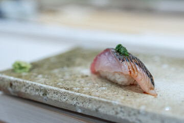 Japanese jack mackerel nigiri sushi highlights its glossy surface and slight charring. The soft...