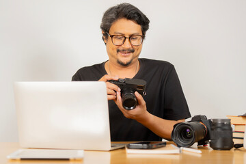 Portrait of happy smiling adult man photographer sitting at a desk and holding a camera